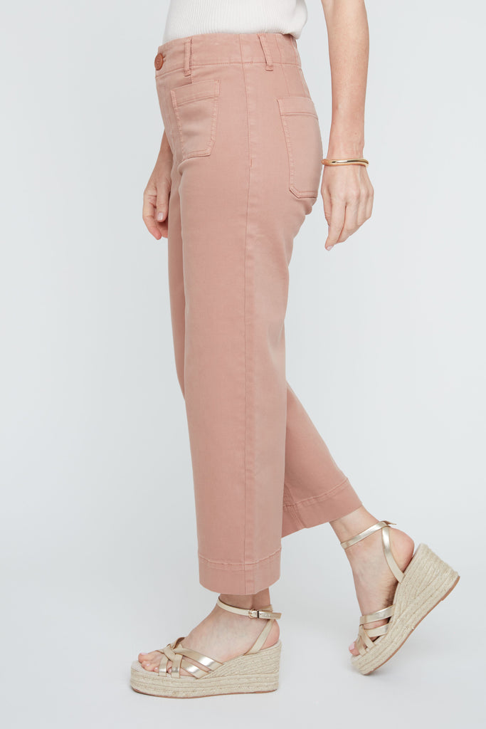 Person wearing pink pants and gold sandals on a white background