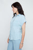 Woman wearing a light blue shirt and pants against a white background