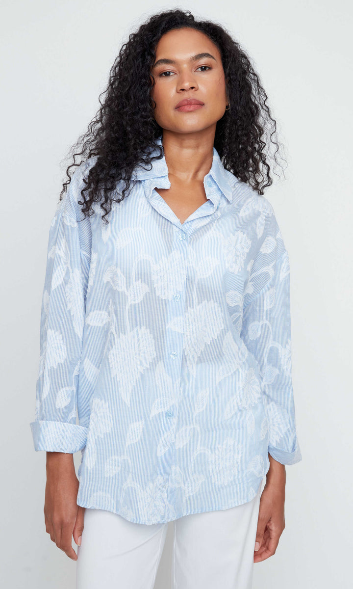 Woman wearing a light blue floral blouse against a white background