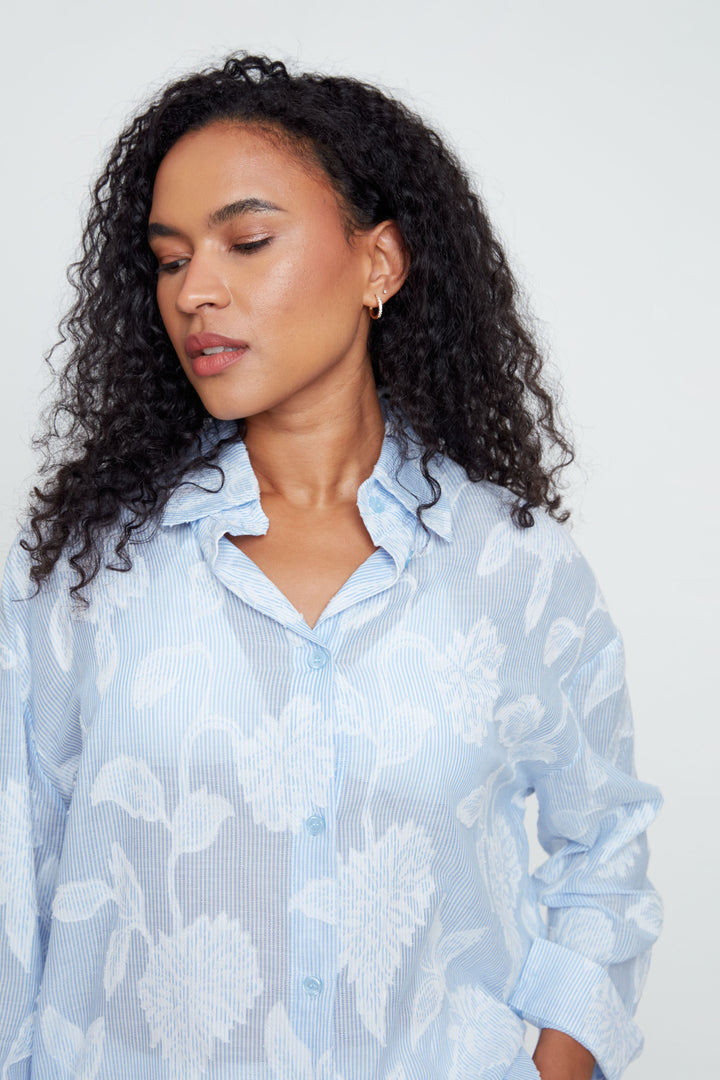 Woman wearing a light blue floral blouse against a plain background