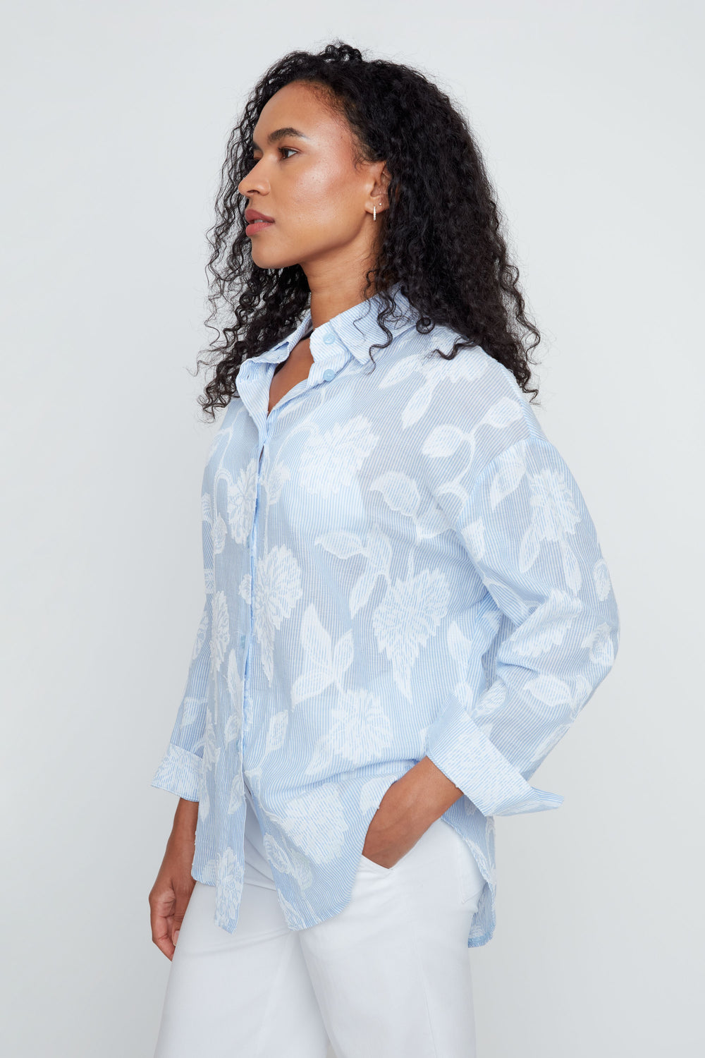 Woman wearing a light blue floral blouse against a white background