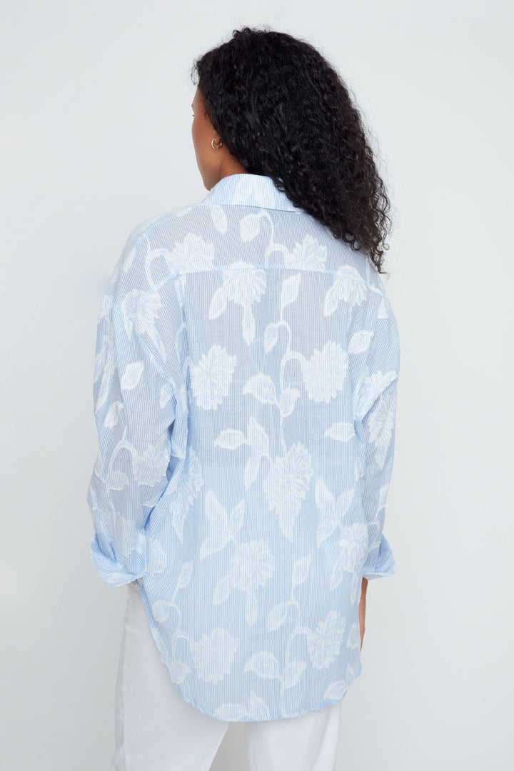 Person wearing a light blue floral patterned shirt against a white background