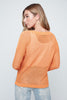 Woman wearing an orange knitted sweater against a plain background