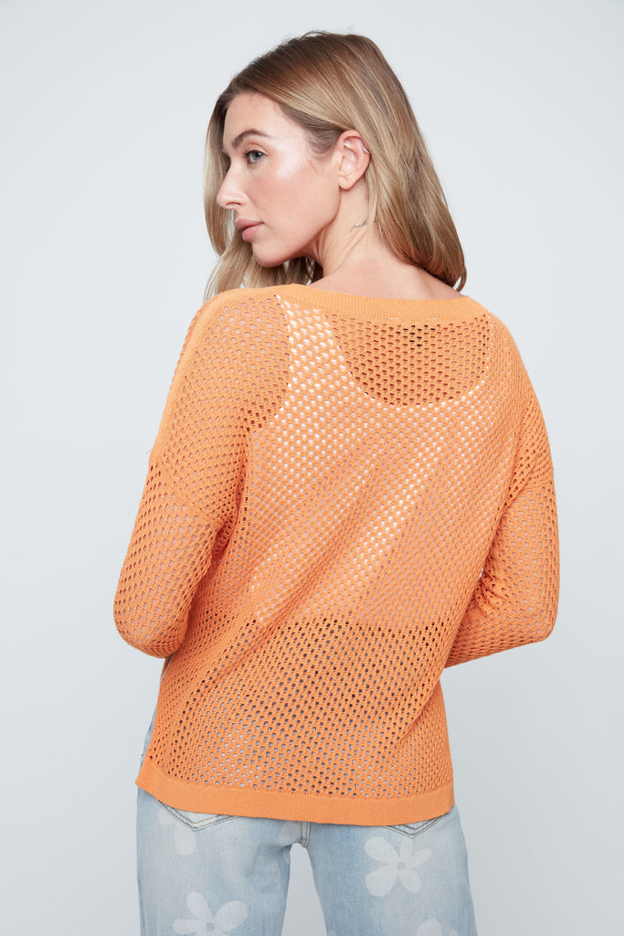 Woman wearing an orange knitted sweater against a plain background