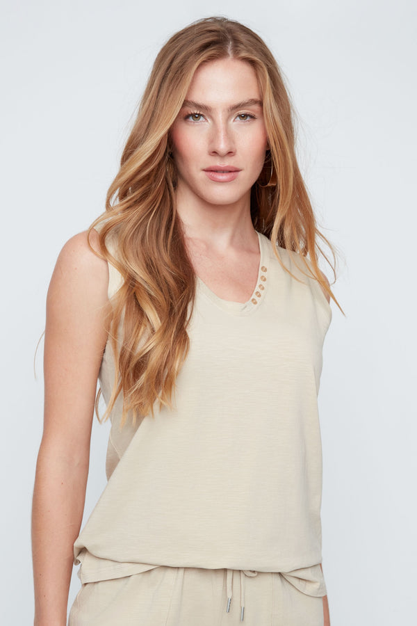 Woman wearing a beige sleeveless top and shorts on a white background