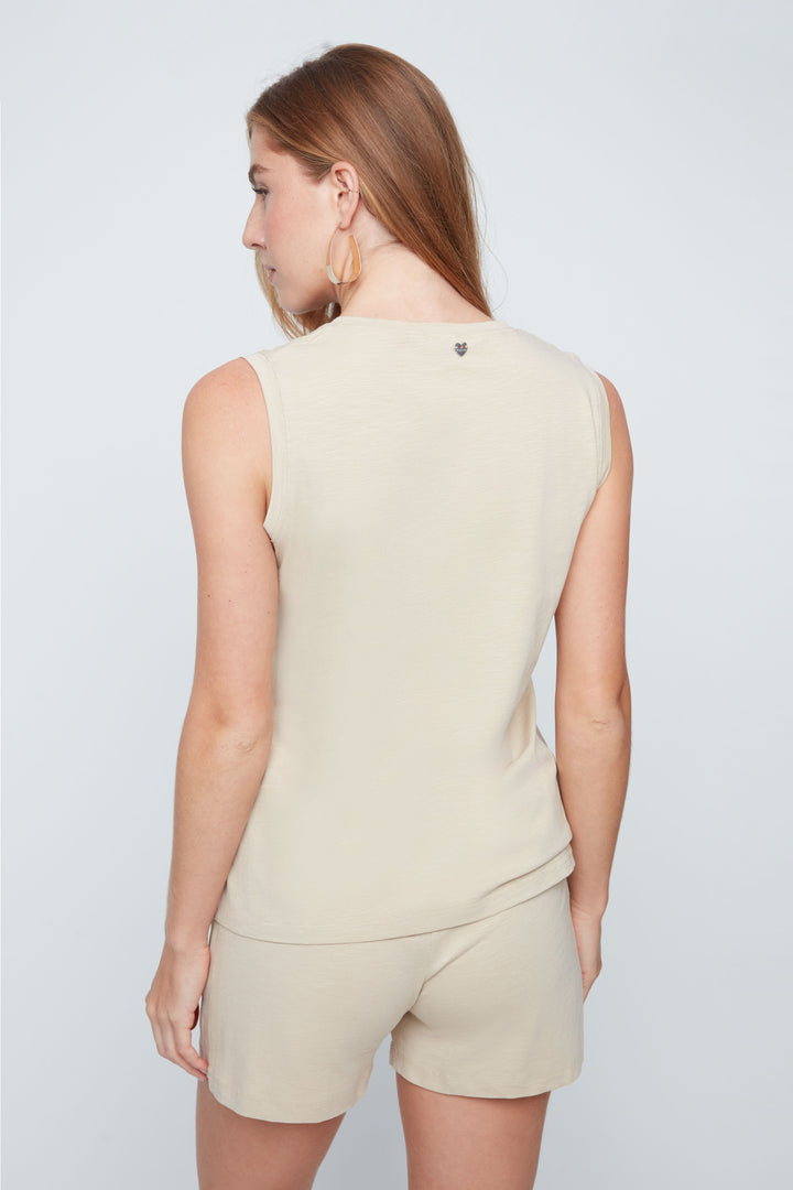 Woman wearing a beige sleeveless top and shorts set on a light gray background