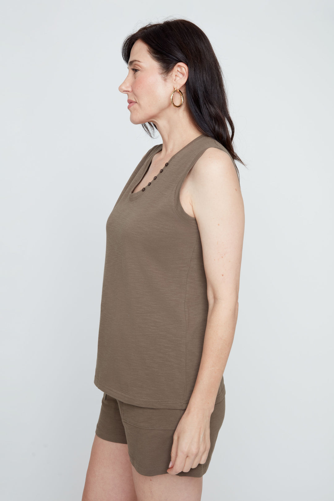 Woman wearing a brown sleeveless top and shorts on a white background