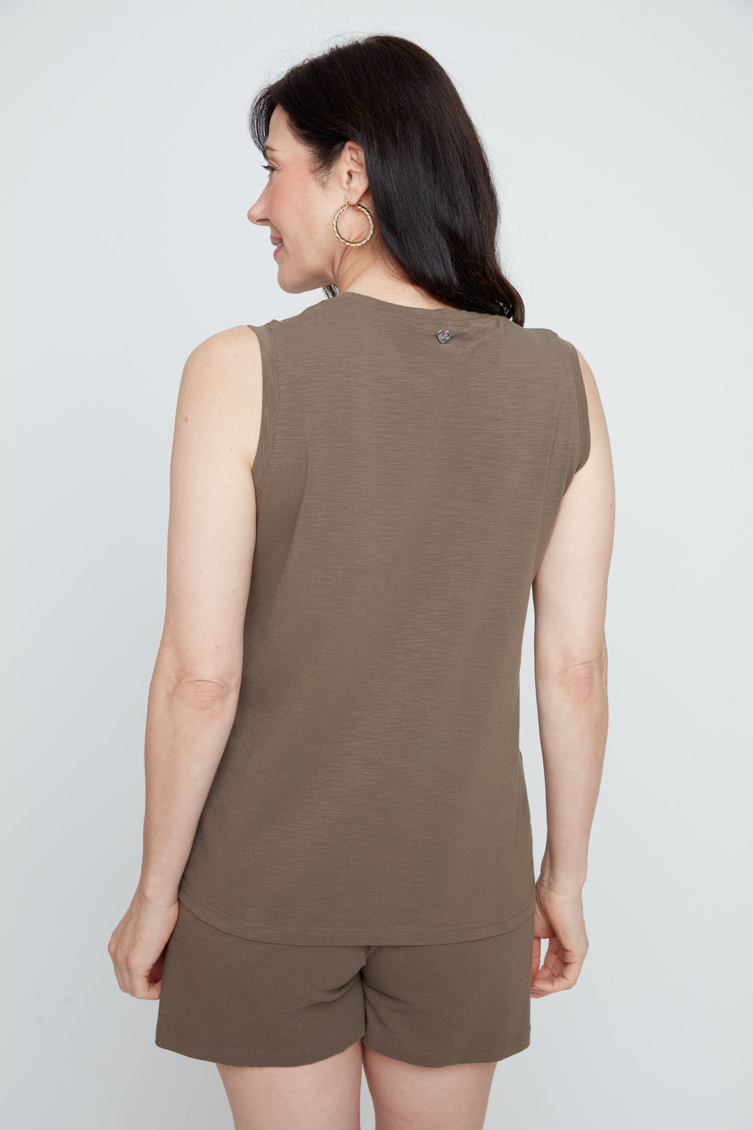Woman wearing a brown sleeveless top and shorts on a white background