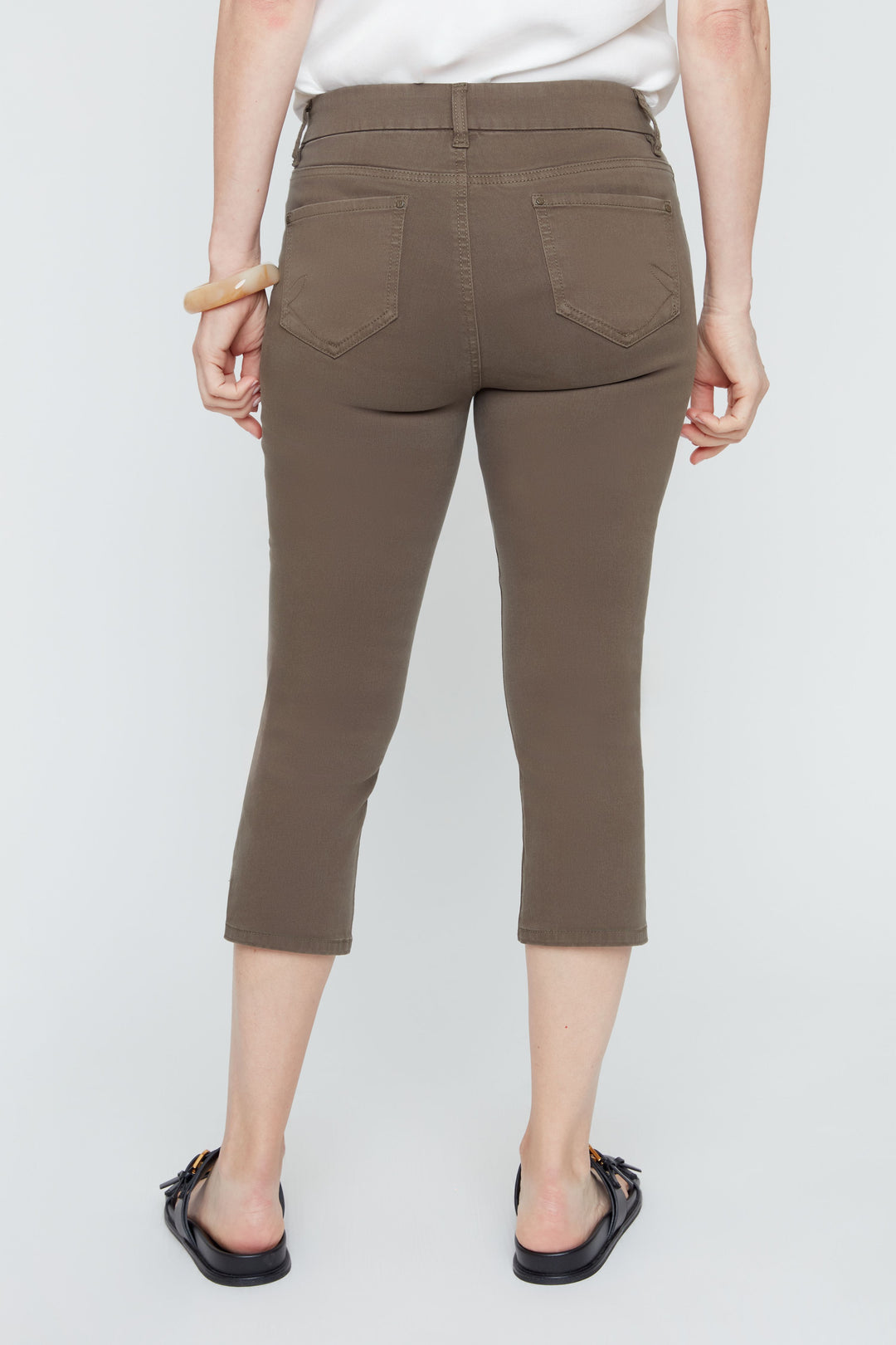 Person wearing brown capri pants on a white background