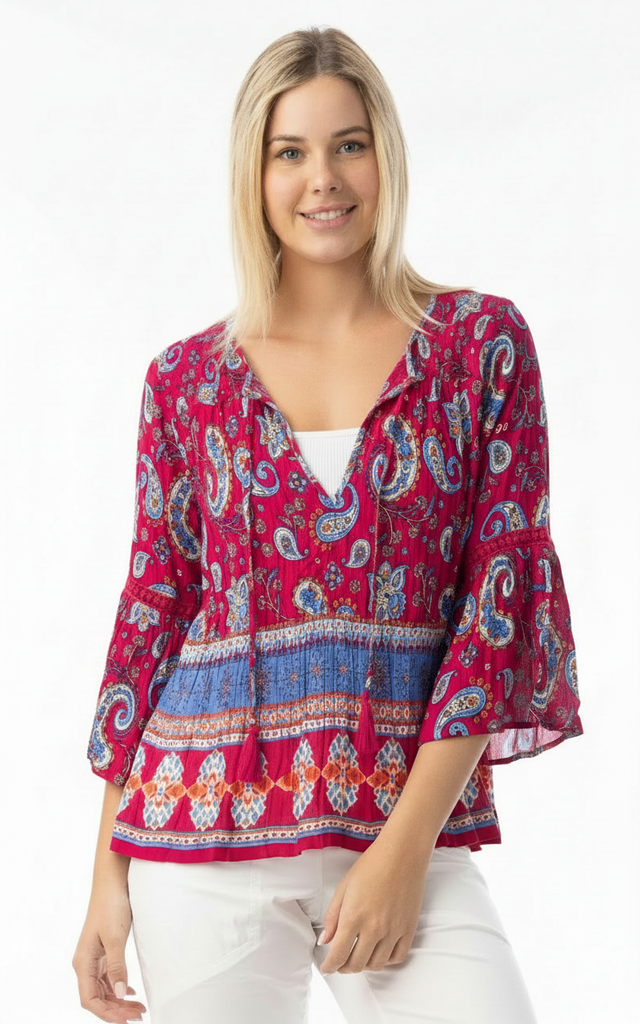 Woman wearing a red patterned blouse with white pants on a white background