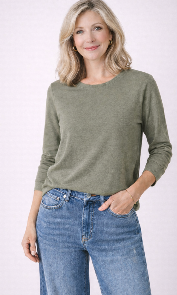 Woman wearing a green sweater and blue jeans on a white background