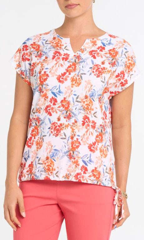 Woman wearing a floral top and pink pants on a white background