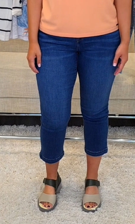 Person wearing blue jeans and a peach top on a carpeted floor.