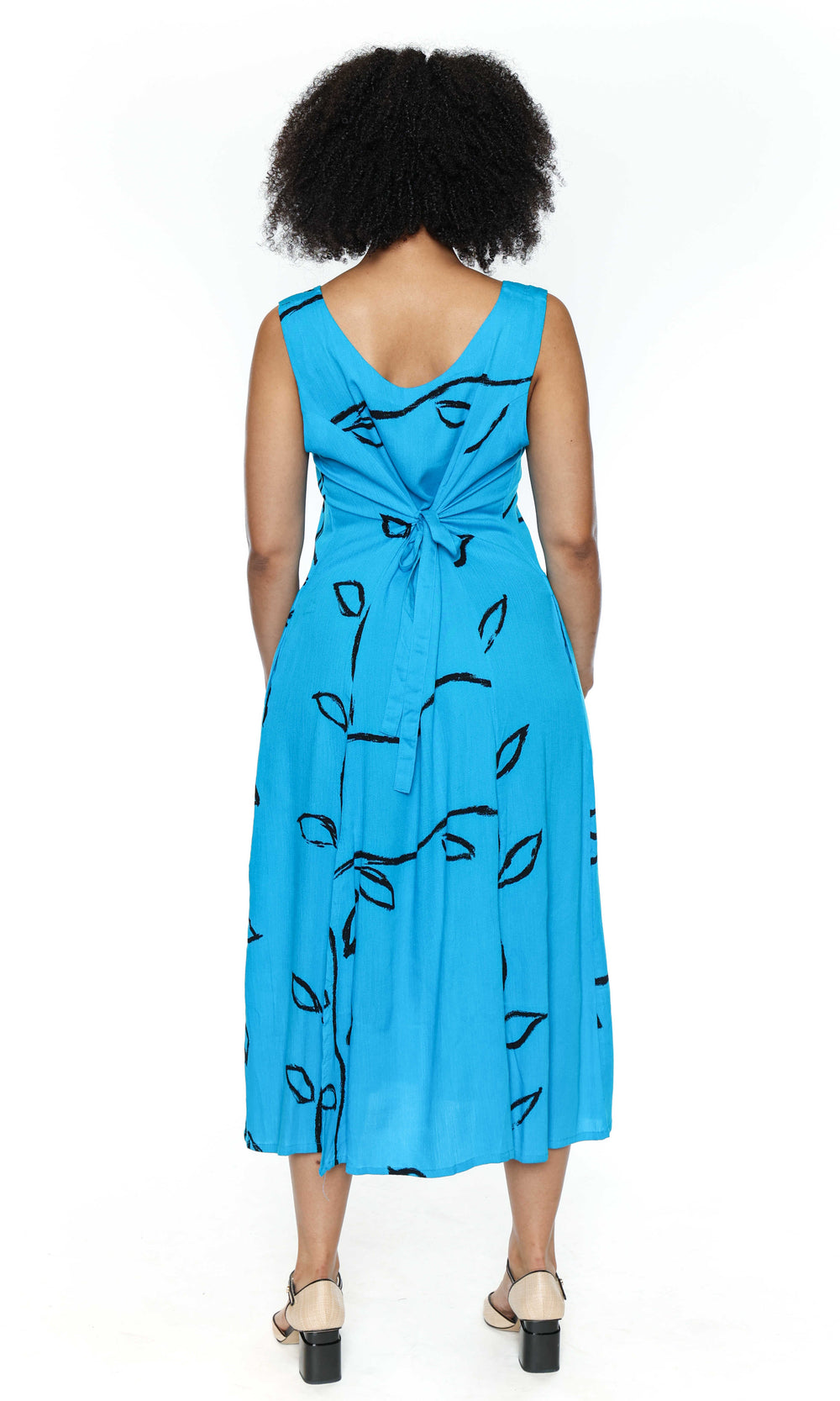 The back of a woman wearing a blue dress with black patterns on a white background