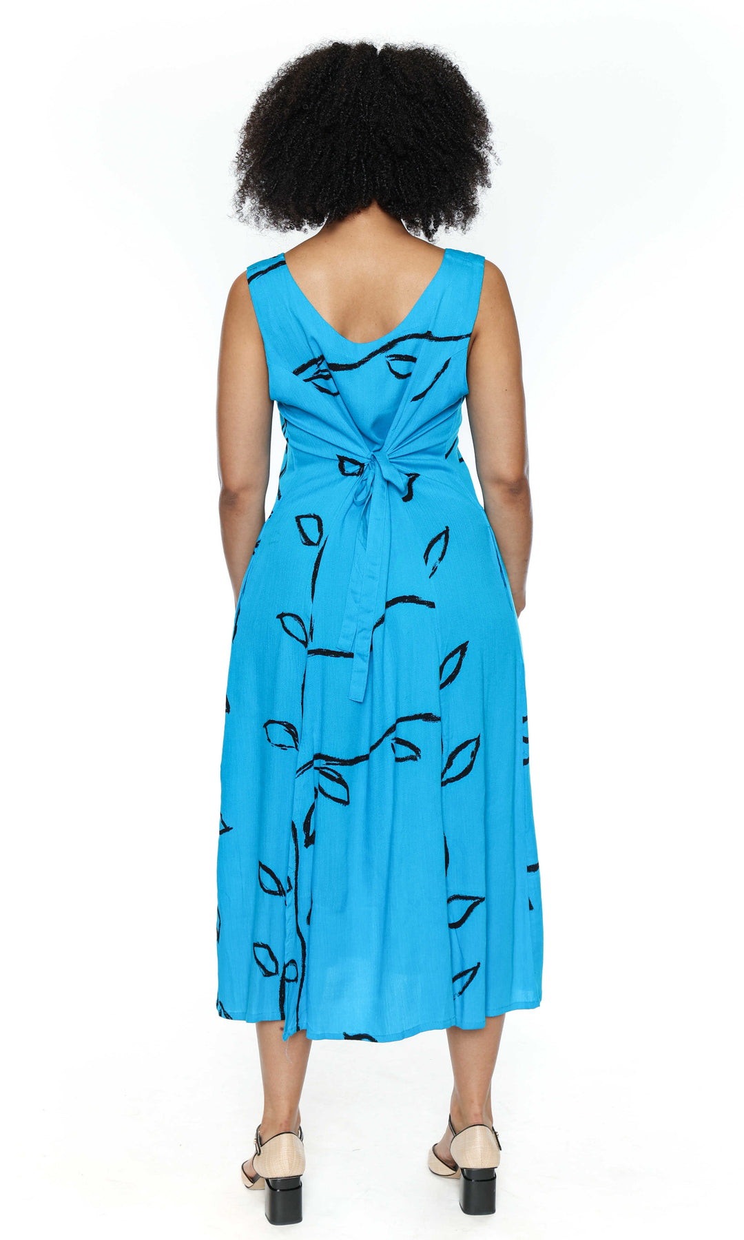 The back of a woman wearing a blue dress with black patterns on a white background