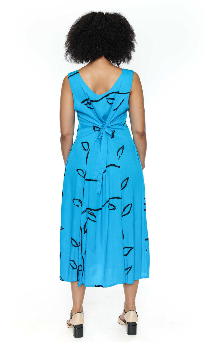The back of a woman wearing a blue dress with black patterns on a white background
