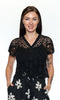 Woman wearing a black lace top with floral pants on a white background