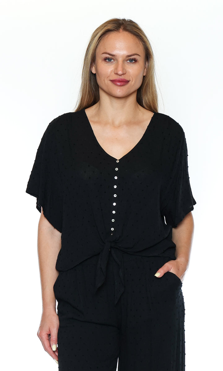 Woman wearing a black outfit with a button detail on a white background