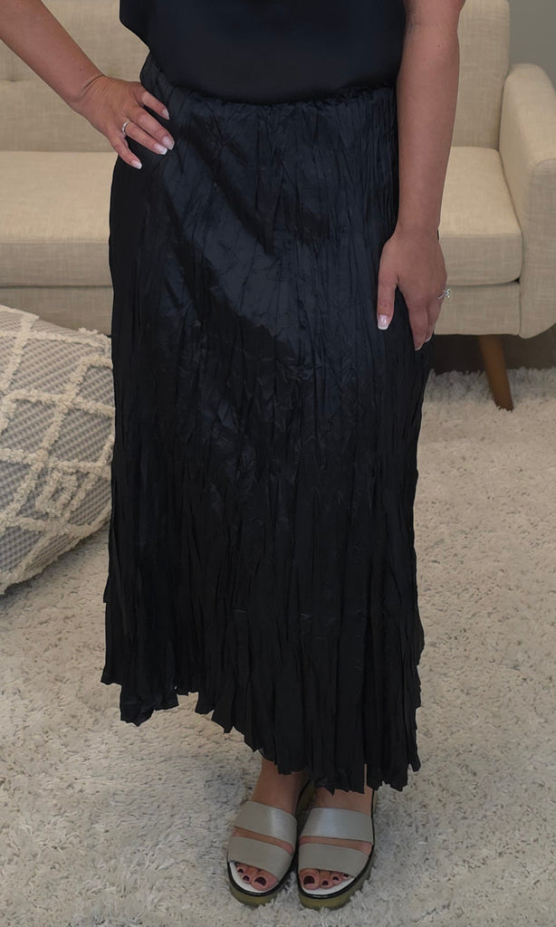 Person wearing a black pleated skirt in a home setting