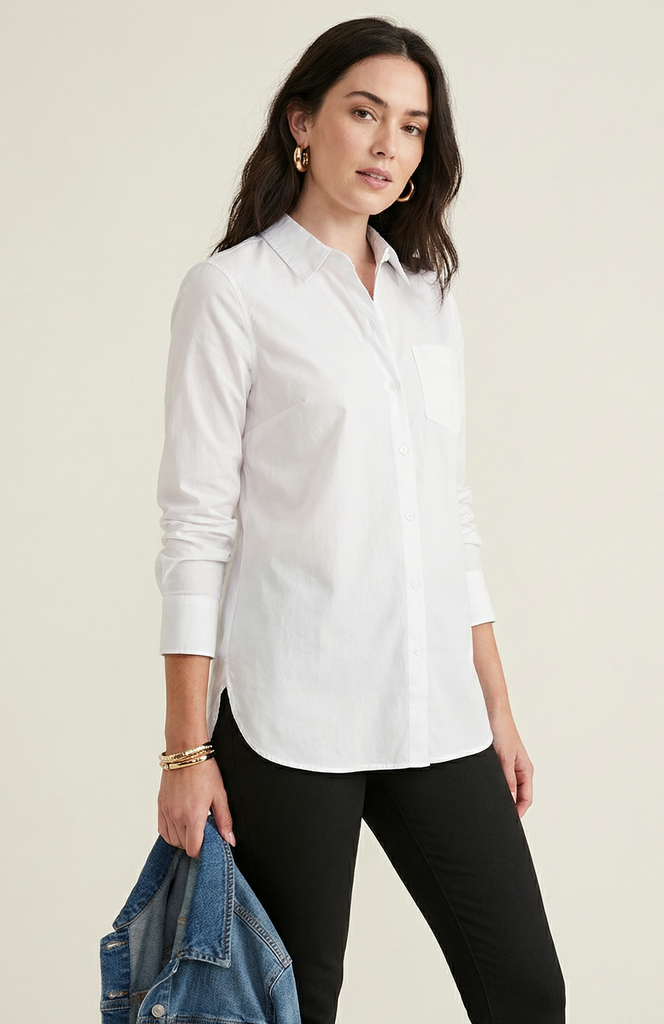 Woman wearing a white shirt and black pants holding a denim jacket on a beige background
