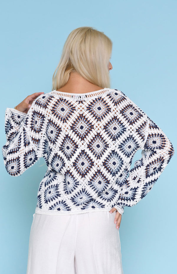 Model wearing lightweight crochet diamond pattern knit sweater with long sleeves and crew neckline