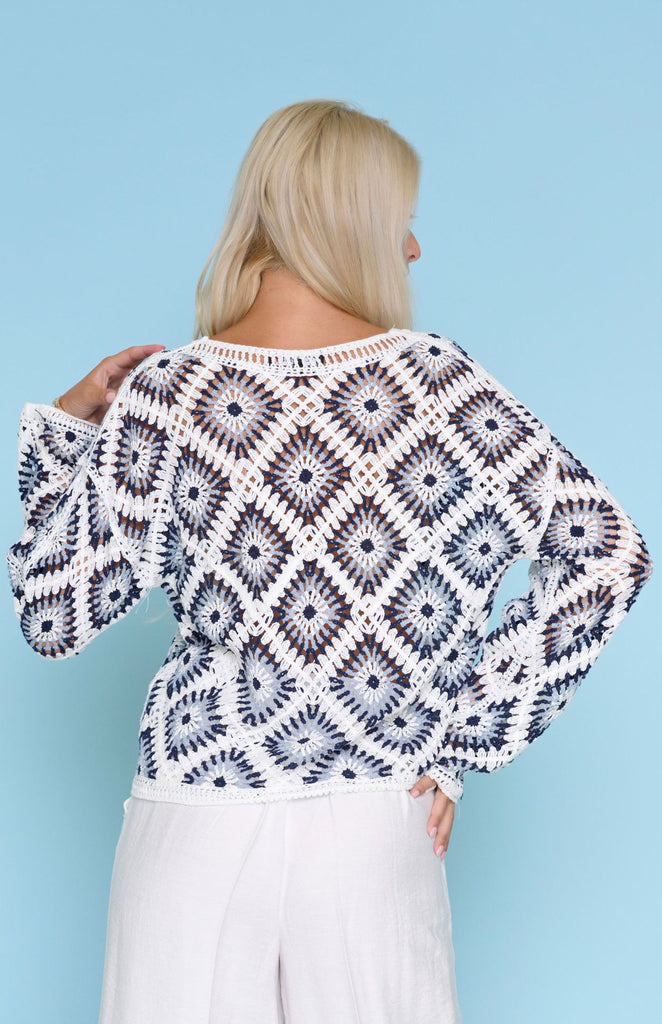 Model wearing lightweight crochet diamond pattern knit sweater with long sleeves and crew neckline