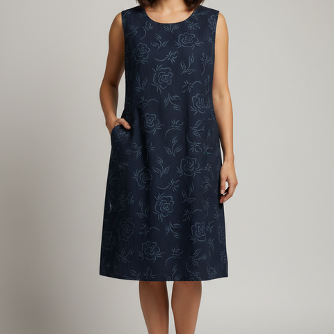 Woman wearing a navy dress with floral pattern on a plain background