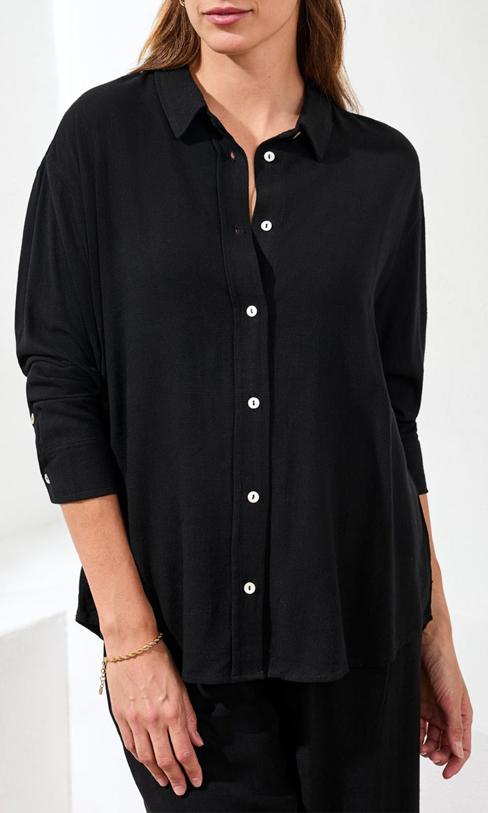 Woman wearing a black button-up shirt on a white background