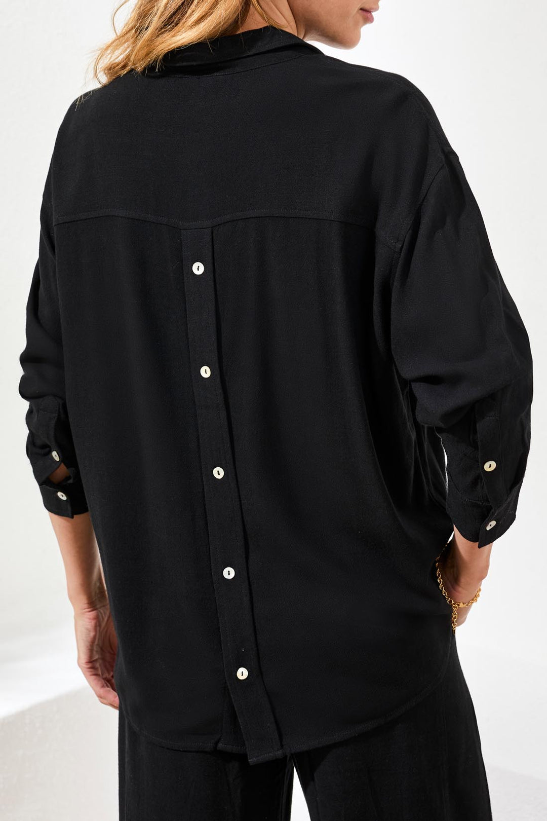 Black button-up shirt worn by a person on a white background