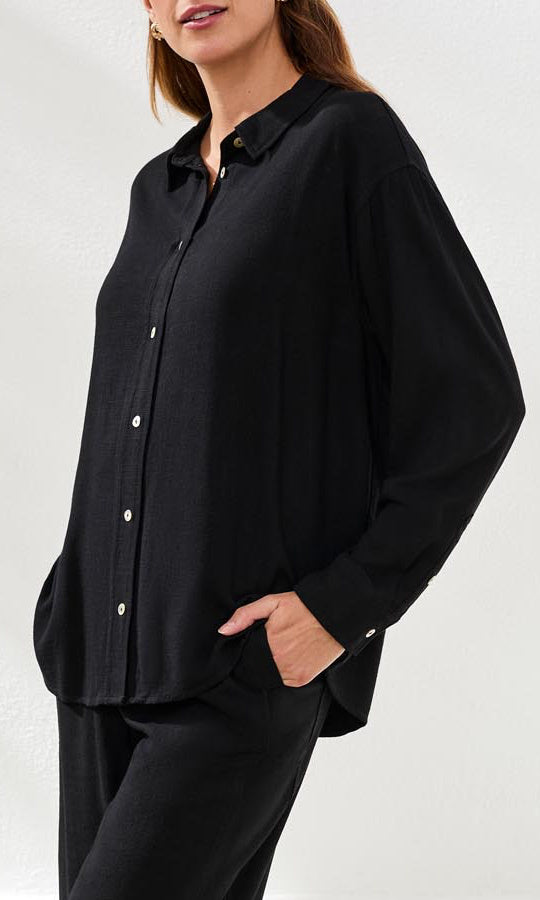 Person wearing a black button-up shirt and pants on a white background