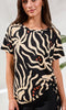 Woman wearing a black and beige patterned top with a blurred background