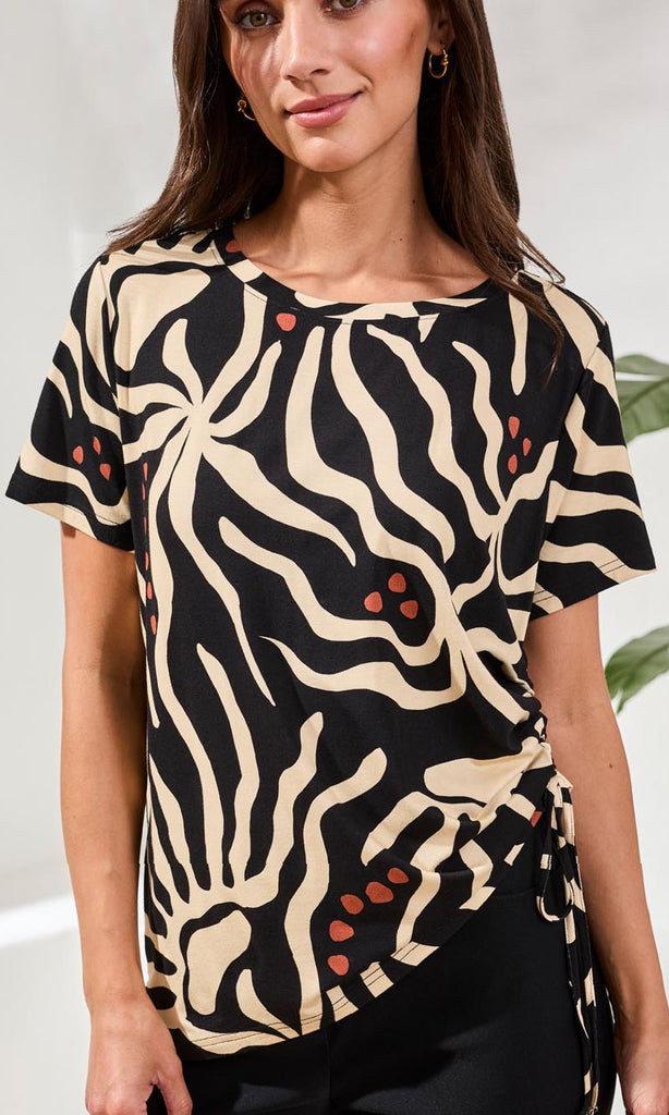Woman wearing a black and beige patterned top with a blurred background