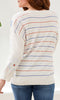 Person wearing a cream sweater with colorful horizontal stripes on a white background