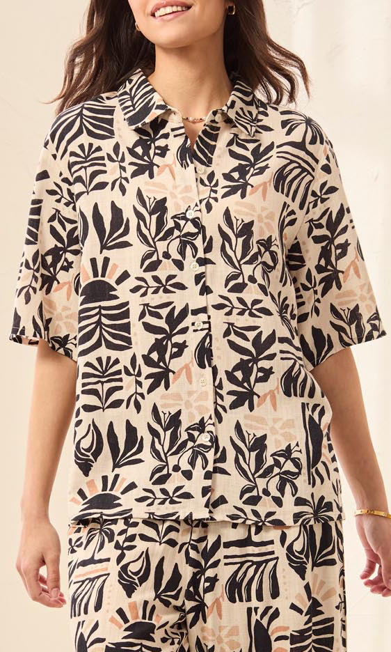 Woman wearing a patterned outfit with black and beige design on a neutral background