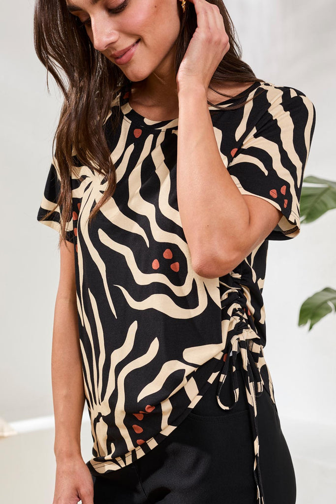 Woman wearing a black and beige patterned top with a white background