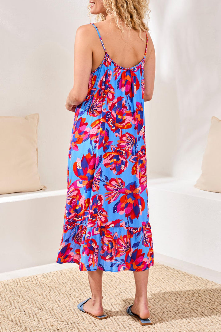 Woman wearing a colorful floral dress sitting on a couch.