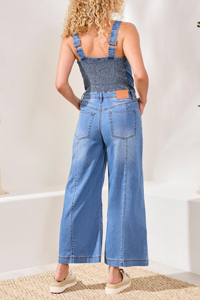 Person wearing a denim jumpsuit with a plain background