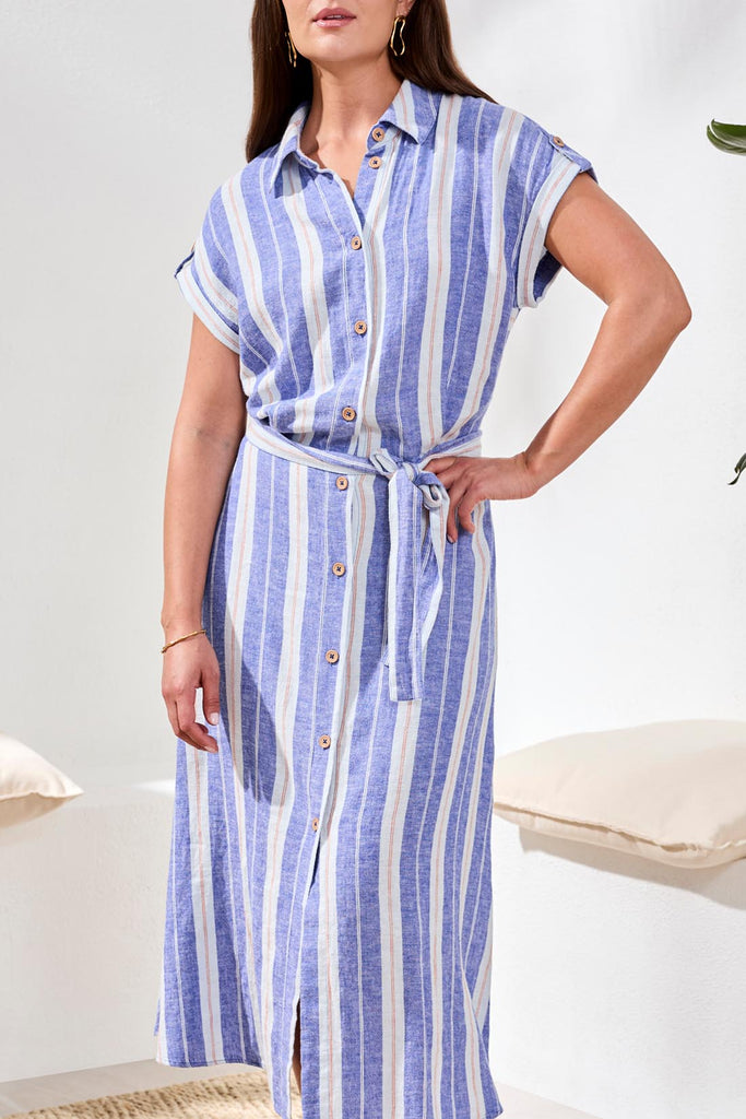 Woman wearing a blue and white striped dress with a belt in a minimal indoor setting.