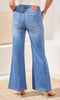 Person wearing blue flared jeans with a neutral background