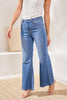 Person wearing blue jeans and a white top on a neutral background