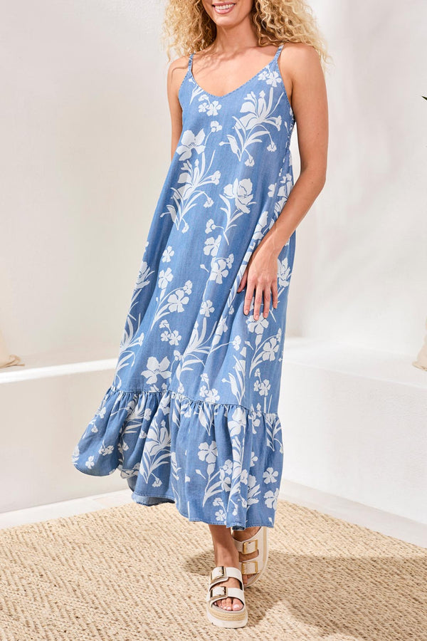 Woman wearing a blue floral dress standing on a textured surface with a white background