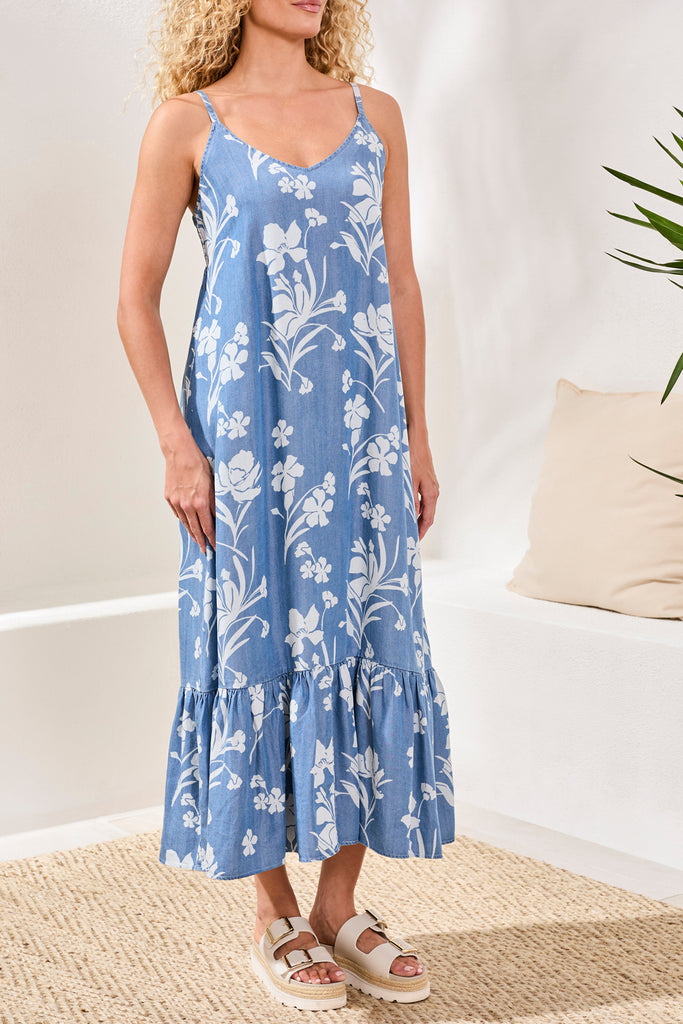 Woman wearing a blue floral dress in a minimal indoor setting