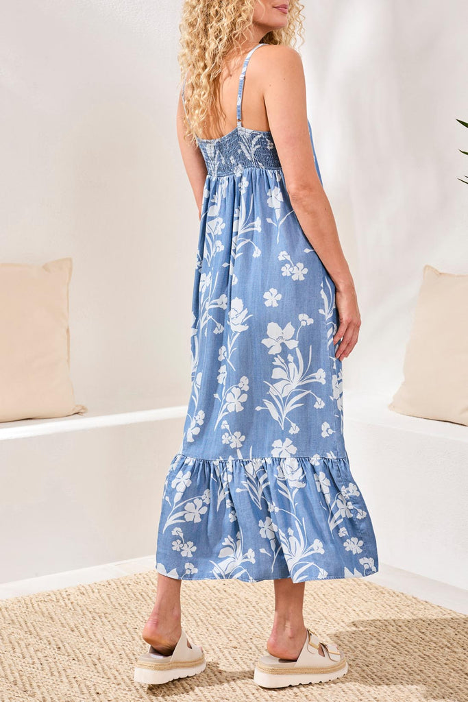 Woman wearing a blue floral dress in a minimal indoor setting