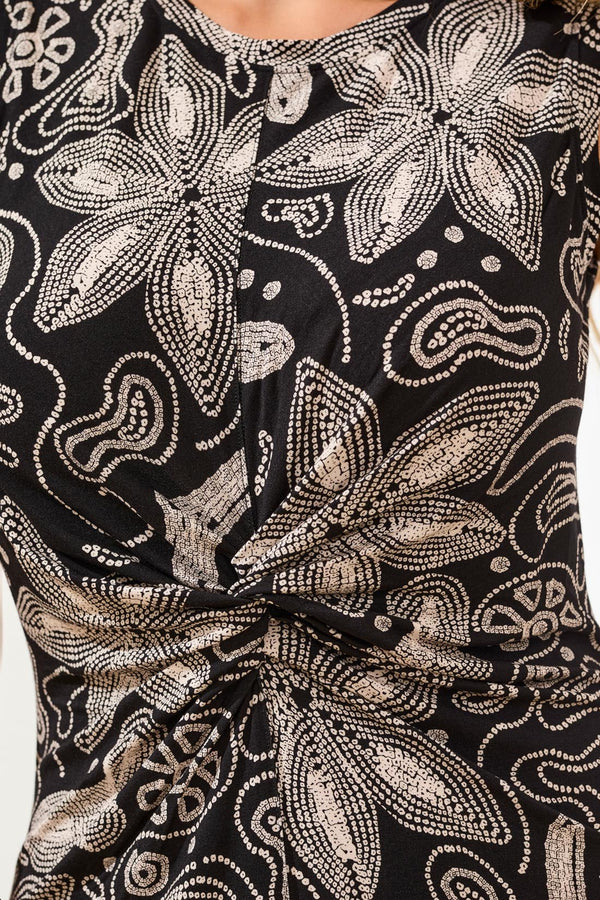 Close-up of a black dress with gold floral and paisley patterns.