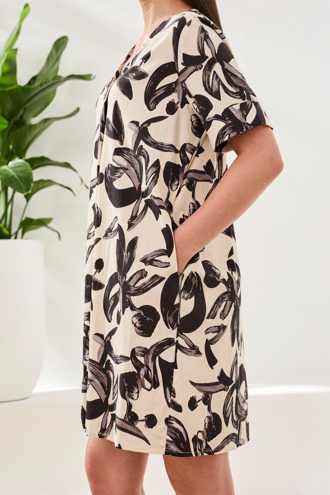 Person wearing a floral dress with a plant in the background