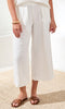 Person wearing white wide-leg pants and brown sandals on a light background