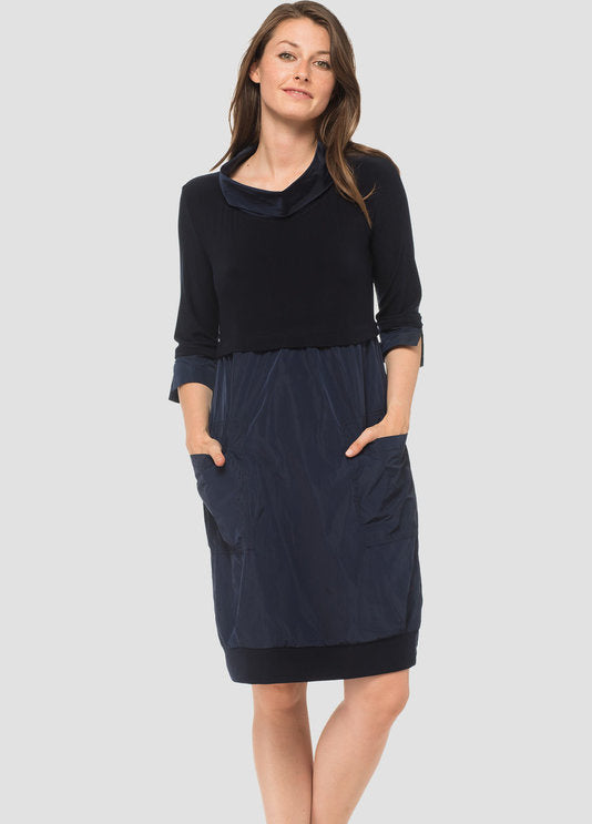 A knee-length navy dress with a mock neckline, long cuffed sleeves, and front pockets.